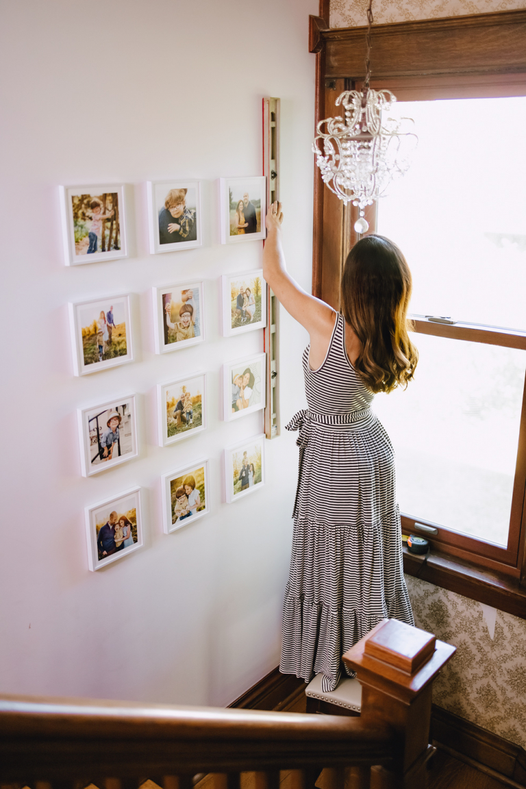 woman decorating stairwell with family photos