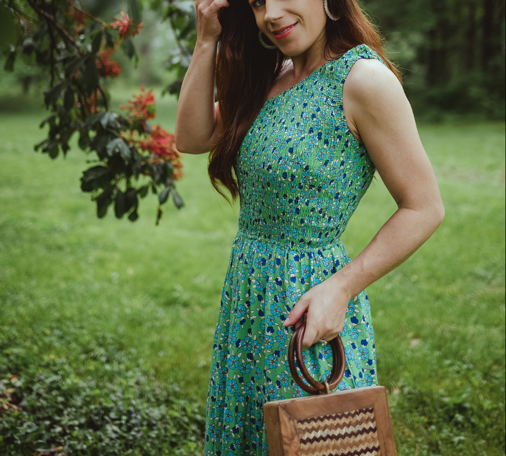 woman in garden with one shoulder green floral dress