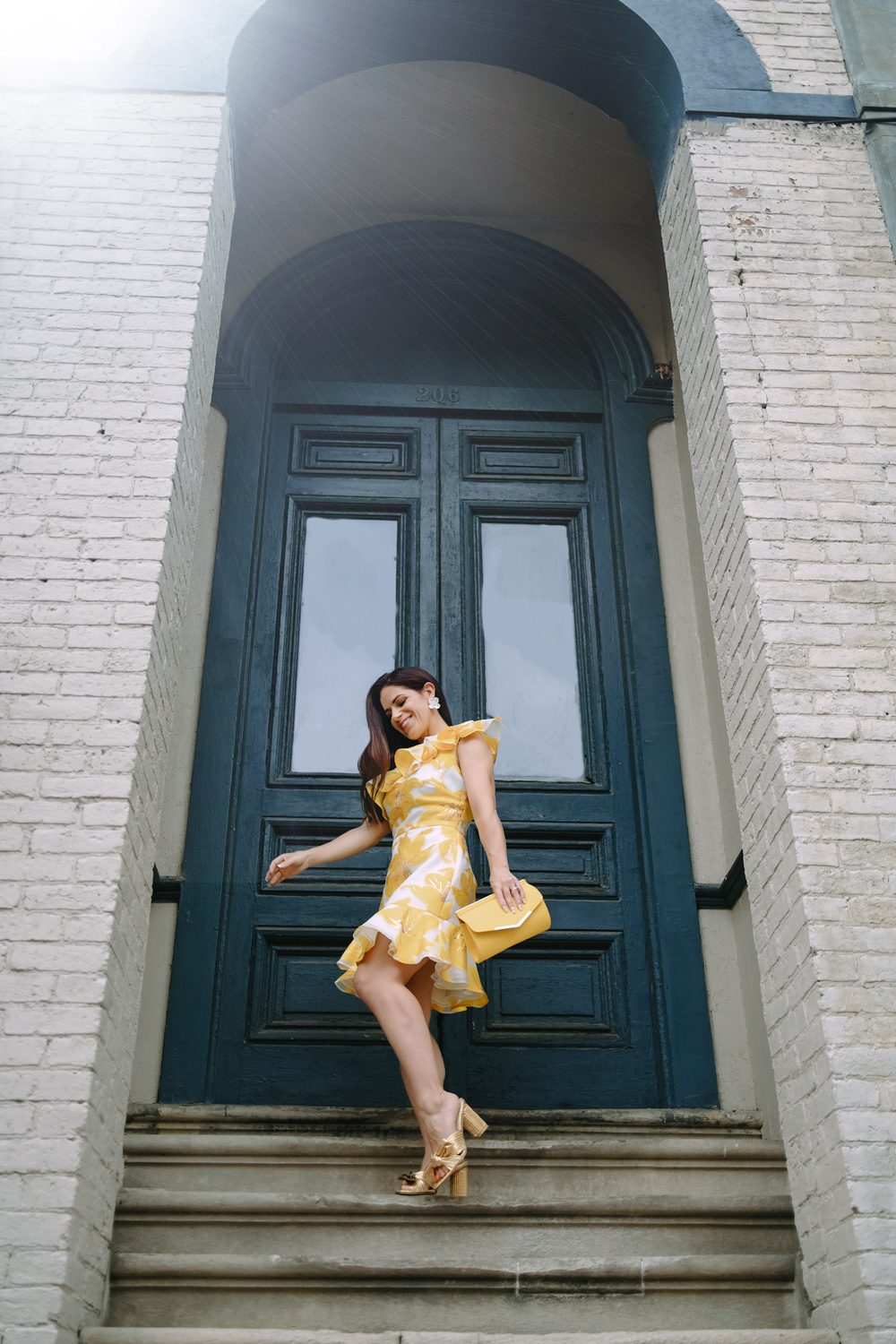 woman in yellow floral dress and gold heels